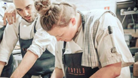 female-chef-preparing-food-while-others-look-on