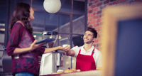 A barista serving a customer in a cafe.png