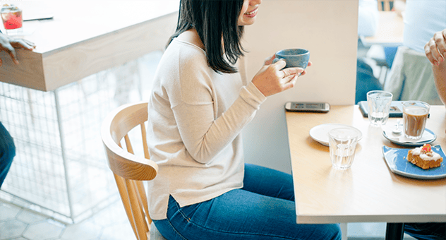 A woman enjoying a cup of coffee in a restaurant.png