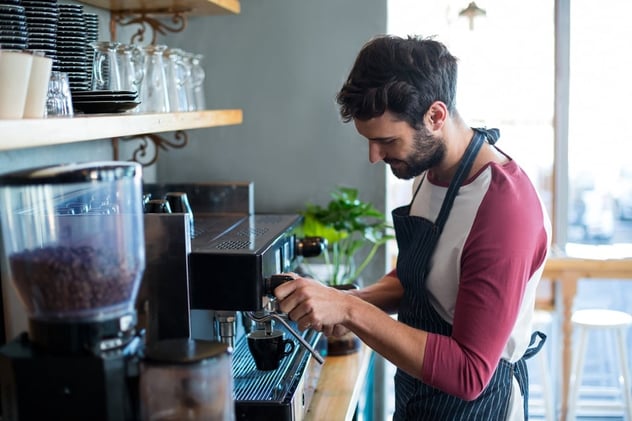 Smiling waiter making cup of coffee in cafe.jpeg