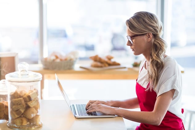 Waitress sitting at table and using laptop in cafx92xA9.jpeg